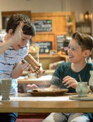 Dos niños disfrutan cocinando juntos en un restaurante histórico en Expedition Archeon, un parque en Holanda.