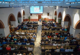 Pubblico seduto in una sala conferenze presso Expedition Archeon, parco vacanze in Olanda Meridionale.