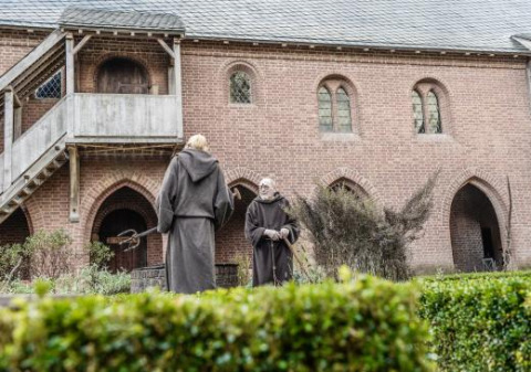 Dos personas con túnicas medievales caminan por un jardín de un monasterio en Expedition Archeon, Holanda del Sur.