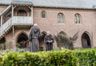 Dos personas con túnicas medievales caminan por un jardín de un monasterio en Expedition Archeon, Holanda del Sur.