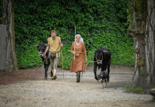 Dos personas con ropa histórica guían vacas y un perro por Expedition Archeon, parque en Holanda Meridional, Países Bajos.