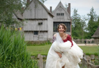 En smilende kvinde i brudekjole foran traditionelle bygninger i det naturskønne Alphen aan den Rijn, Holland.
