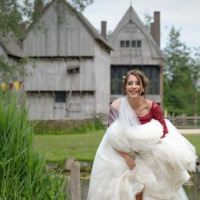 Una mujer sonriente con vestido de novia frente a edificios rústicos en Alphen aan den Rijn, Países Bajos.