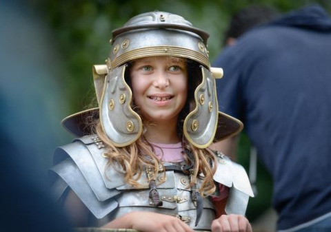 Una bambina sorridente indossa un’armatura romana durante una rievocazione ad Alphen aan den Rijn, Paesi Bassi.