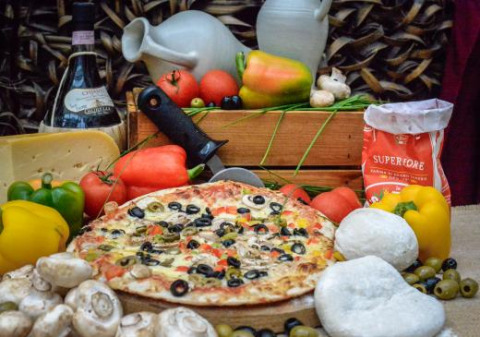Sabrosa pizza con verduras frescas, quesos y vino, presentada como atractivo de Expedition Archeon, Holanda.