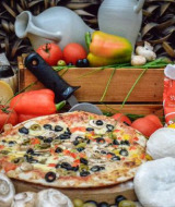 Sabrosa pizza con verduras frescas, quesos y vino, presentada como atractivo de Expedition Archeon, Holanda.