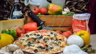 Sabrosa pizza con verduras frescas, quesos y vino, presentada como atractivo de Expedition Archeon, Holanda.