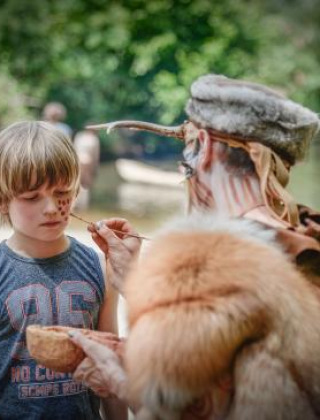 Una persona pinta la cara de un niño al aire libre cerca de Alphen aan den Rijn, Países Bajos, junto al río.
