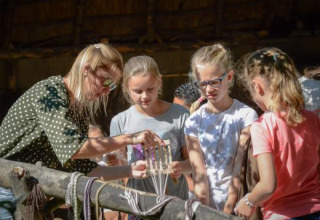 Bambini e un adulto partecipano a un'attività artigianale all'aperto a Expedition Archeon, Sud dell'Olanda, Paesi Bassi.