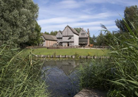 Traditionelle bygninger ved en sø i Expedition Archeon, et feriested i Sydholland, Holland, omgivet af natur.