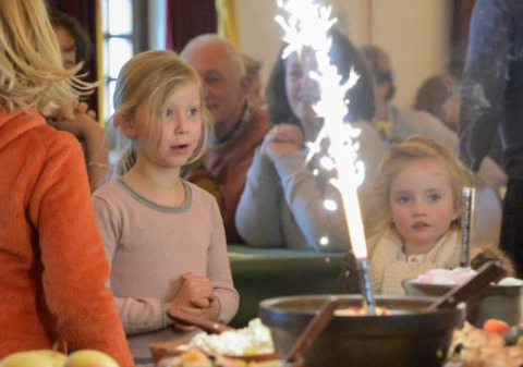 Dos niños sorprendidos miran una tarta con bengalas en Expedition Archeon, parque de vacaciones en Holanda.