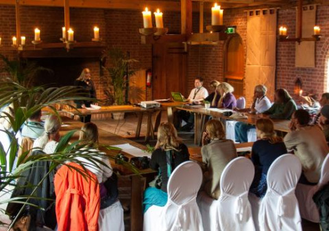 Reunión en Expedition Archeon, parque vacacional en Holanda del Sur, Países Bajos, personas sentadas a la mesa.