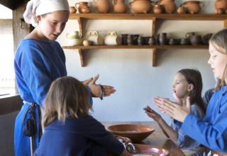 Kinder und Erwachsene in historischer Kleidung bei einem Workshop im Ferienpark Expedition Archeon, Niederlande.