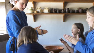Niños y un adulto con trajes históricos participan en un taller en Expedition Archeon en Holanda Meridional.