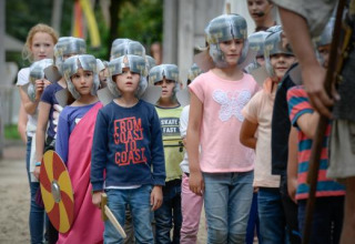 Børn iført hjelm og kostume, der deltager i en historisk rolleleg ved Expedition Archeon i Sydholland.
