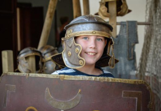 Kind met Romeinse helm en schild tijdens een historische ervaring in Expedition Archeon in Zuid-Holland.