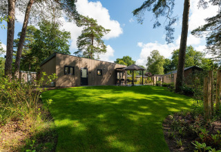 Lodge Loevestein Comfort a Veluwepark de Bosgraaf nei Paesi Bassi, circondata da prato e alberi verdi.