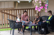 Familia con niños y perro juega a las cartas en la terraza de una tienda safari en Camping de Krabbeplaat.