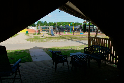 Vista da una tenda safari con bagno al Camping de Krabbeplaat, parco giochi sullo sfondo, Paesi Bassi.