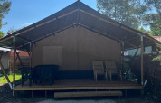 Tienda safari con terraza y muebles exteriores en Camping Luna del Monte, Italia, rodeada de árboles.