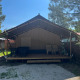 Safari telt med terrasse og havemøbler på Camping Luna del Monte, omgivet af træer under en klar himmel.