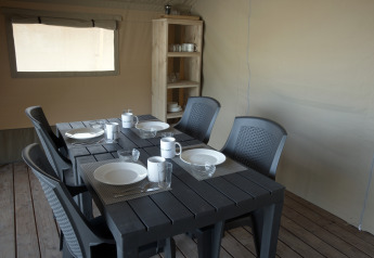 Essbereich im Safarizelt mit vier Gedecken und Regal im Camping Luna del Monte, Italien.