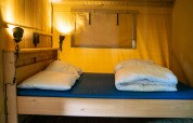 Imagen interior de una cama en tienda safari con colchón azul y edredón en Camping Tussen de Diepen, Países Bajos.