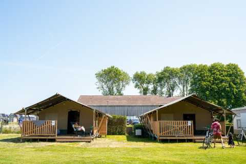 To safaritelte med overdækket veranda og gæster foran, på Camping Tussen de Diepen, Holland.
