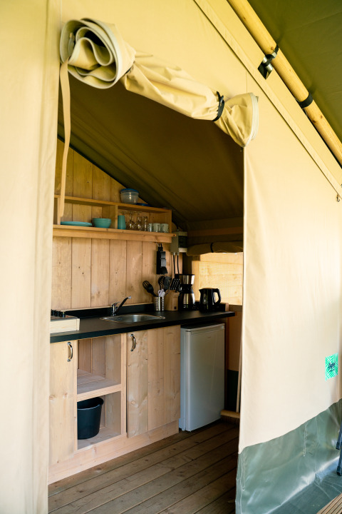 Cucina interna di tenda safari glamping con mobili in legno al Camping Tussen de Diepen, Paesi Bassi.