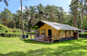 Tienda safari con porche y zona de estar en un entorno verde en Familiepark Goolderheide, Bélgica.