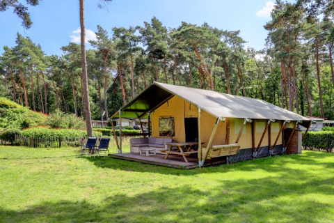 Tenda safari con veranda e posti a sedere immersa nel verde a Familiepark Goolderheide, Belgio.