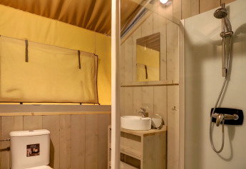 Indvendigt billede af badeværelse i safaritelt med toilet, håndvask, spejl og brusebad i Belgien.