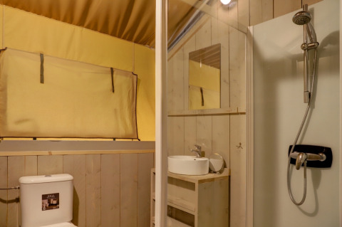 Interieur van een safaritentbadkamer met toilet, wastafel, spiegel en douche in Goolderheide, België.