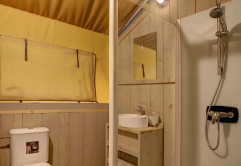 Vista interna del bagno in tenda safari con WC, lavandino, specchio e doccia a Goolderheide, Belgio.