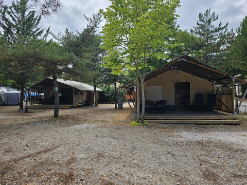 Safari-Zelt mit sanitären Einrichtungen auf Camping Luna del Monte in Italien, umgeben von Bäumen.