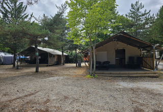 Tienda safari con instalaciones sanitarias en Camping Luna del Monte, Italia, rodeada de árboles y naturaleza.