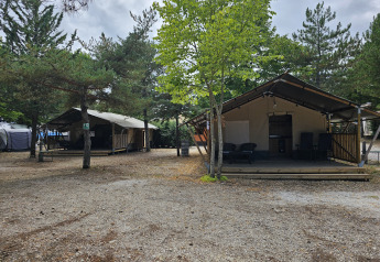 Tienda safari con instalaciones sanitarias en Camping Luna del Monte, Italia, rodeada de árboles y naturaleza.