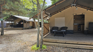 Safari tent with private deck and sanitary facilities, surrounded by trees, perfect for a glamping experience.