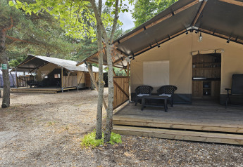 Tienda safari con terraza privada y servicios sanitarios, rodeada de árboles, ideal para una experiencia glamping.
