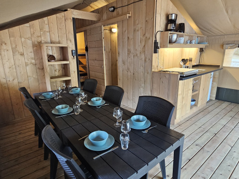 Zona pranzo e cucina in una tenda safari con servizi privati al Camping Luna del Monte, Italia.