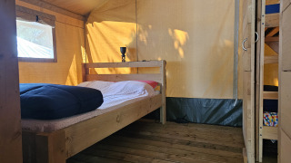 Innenansicht eines Safari-Zeltes mit Holzboden, Doppelbett und Etagenbett auf Camping Luna del Monte in Italien.