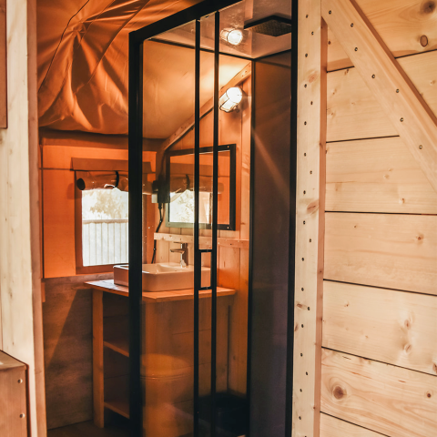 Vista interior de una tienda safari con instalaciones sanitarias privadas en Camping Luna del Monte, Italia.