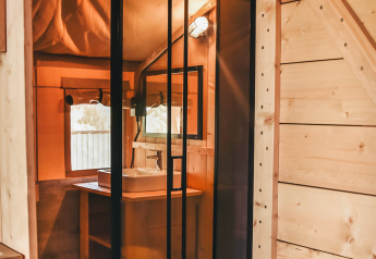 Vista interior de una tienda safari con instalaciones sanitarias privadas en Camping Luna del Monte, Italia.