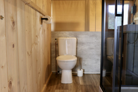 Badkamer met houten panelen, toilet en douche in safaritent op Camping de Heerlijkheid Vorenseinde.