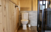 Baño con paneles de madera, inodoro y ducha en tienda safari en Camping de Heerlijkheid Vorenseinde.