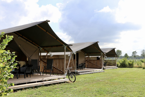 Safari-Zelte mit eigener Sanitäranlage und Terrasse auf einer Wiese, ideal zum komfortablen Campen.