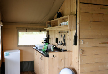 Interno di una tenda safari con mobili in legno e cucina al Camping de Heerlijkheid Vorenseinde, Paesi Bassi.