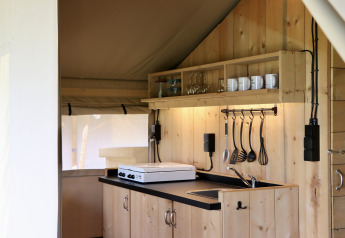 Angolo cottura in legno in tenda safari con utensili appesi al Camping de Heerlijkheid Vorenseinde.