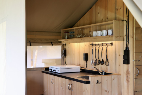 Houten kitchenette in een safaritent met fornuis en keukengerei op Camping de Heerlijkheid Vorenseinde.