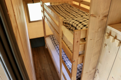 Binnenaanzicht van een safaritent bij Camping de Heerlijkheid Vorenseinde met houten stapelbedden.